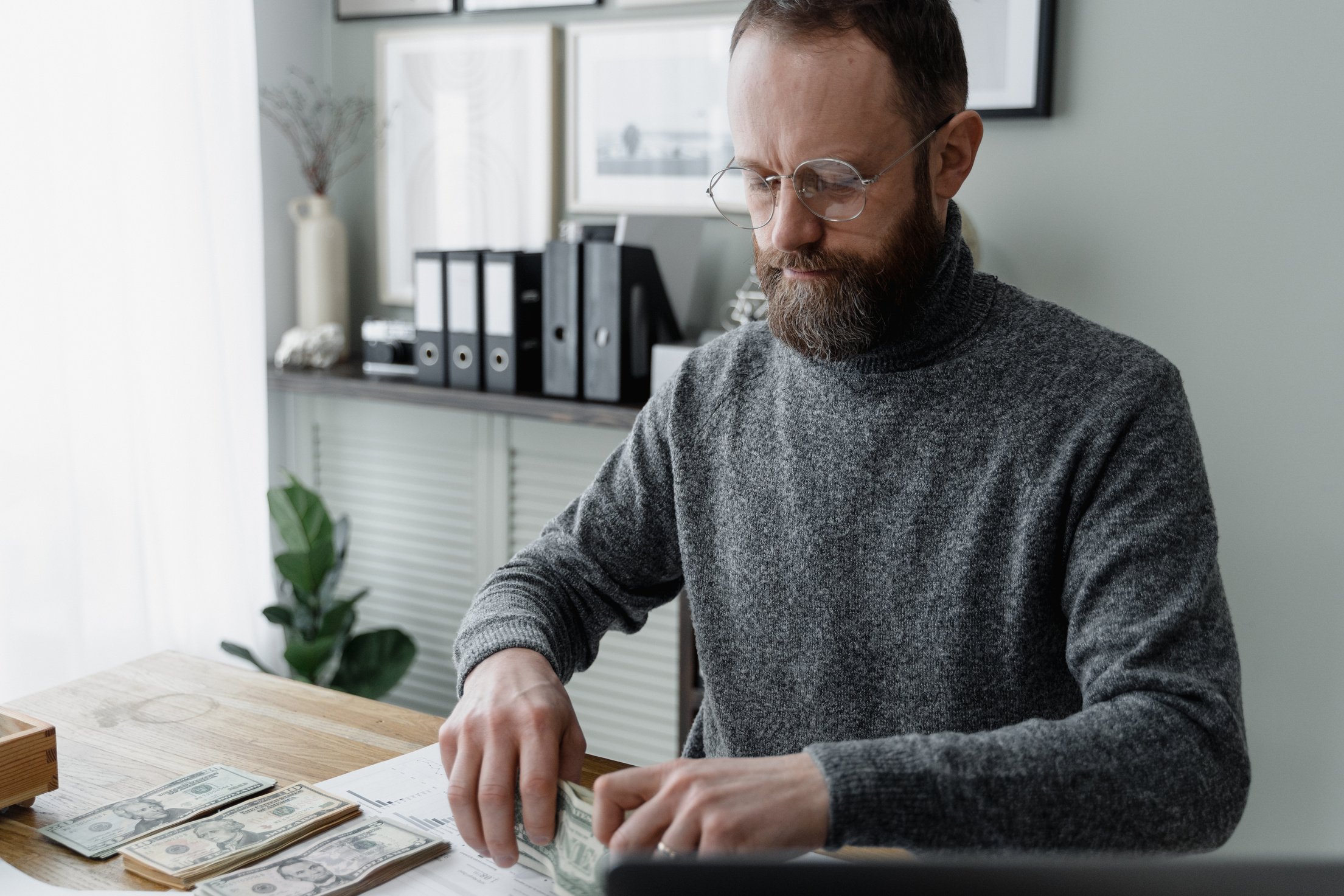 Man in Gray Sweater Wearing Eyeglasses Holding Paper Money