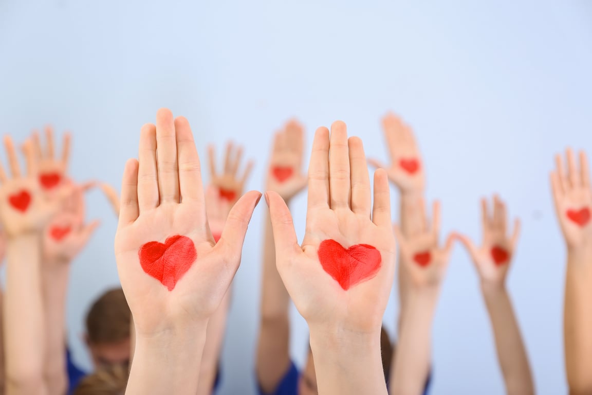 Raised in Air Hands with Drawn Hearts on Palms against Light Background